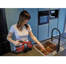 Vrouw gebruikt een ontstoppingsveer van Einhell om een afvoerpijp te ontstoppen.