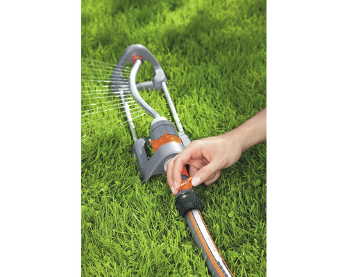 Werkende gazonsproeier met hand aan de regelaar op gazon