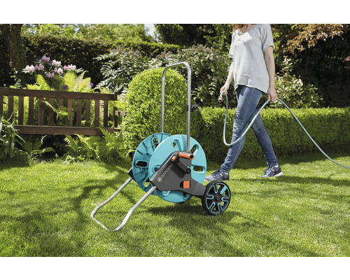 Gardena slangenwagen in de tuin met vrouw die water geeft