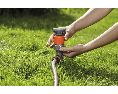 Persoon stelt een gazonsproeier af op het gazon.