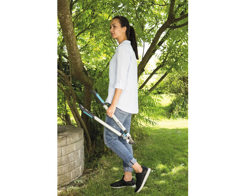 Een vrouw staat in de tuin en houdt een takkenschaar vast.