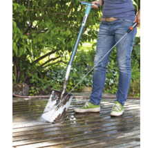 Persoon reinigt een terras met een Gardena terrasreiniger en een waterslang