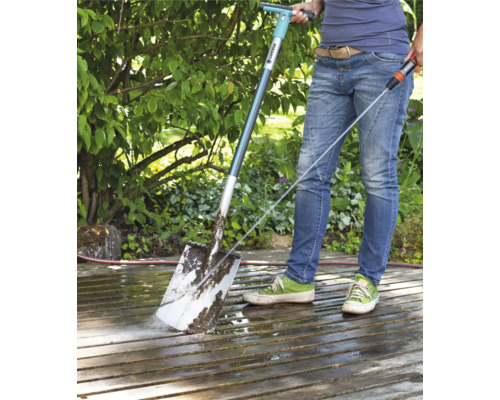 Persoon reinigt een terras met een Gardena terrasreiniger en een waterslang