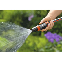 Een hand houdt een Gardena tuinslang vast waar water uit spuit.