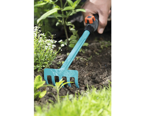 Tuinieren met een kleine hark in de tuin.