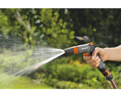 Een hand houdt een tuinspuit vast waar water uitkomt.