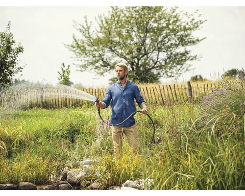 Man besproeit tuin met tuinslang en spuitpistool