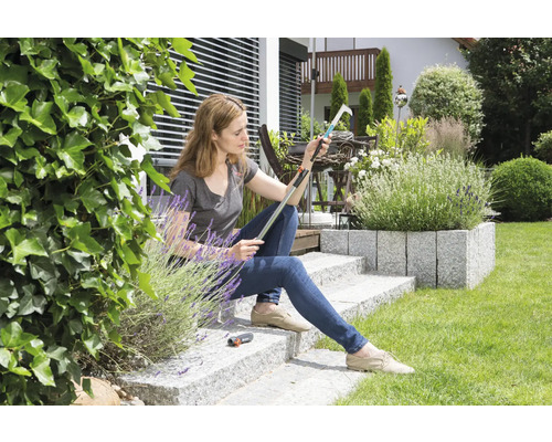 Vrouw zit in de tuin en inspecteert een fruitplukker