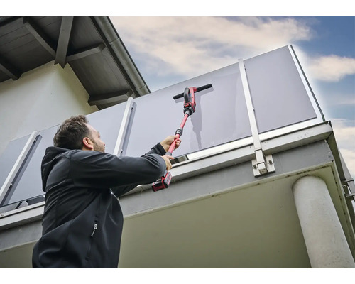 Man reinigt glazen borstwering met een draadloze ruitenreiniger.