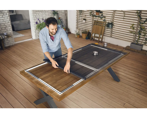 Een man monteert een hor op een houten tafel buiten.