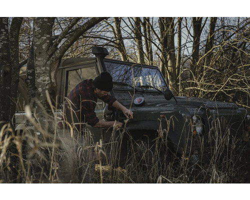 Man bevestigt iets aan een terreinwagen in het veld