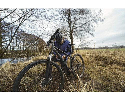 Een man repareert zijn fiets in de natuur