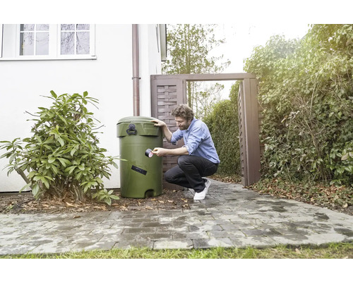 Man repareert een regenton met tape in de tuin.