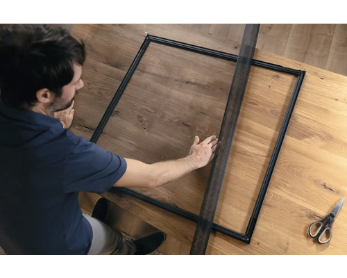 Man monteert een insectenhor op een houten tafel.