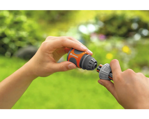 Een persoon verbindt twee Gardena slangstukken.