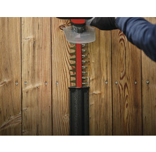 Een heggenschaar knipt voor een houten wand.