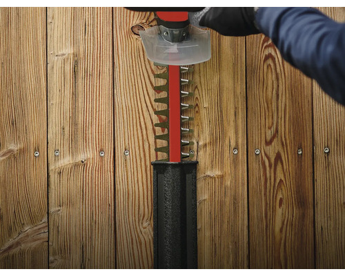 Een heggenschaar knipt voor een houten wand.