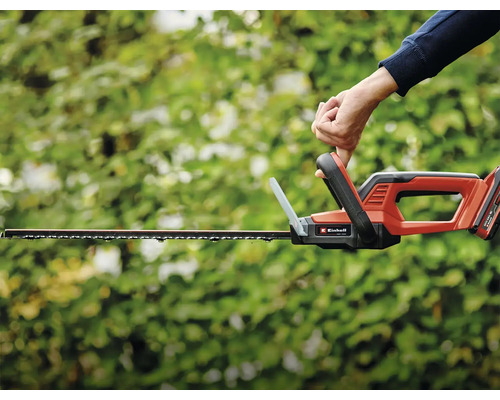Een persoon bedient een Einhell accuheggenschaar om heggen te snoeien.
