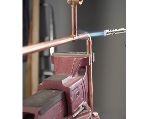 Koperen buis wordt verbonden met een soldeerbout en een werkbank