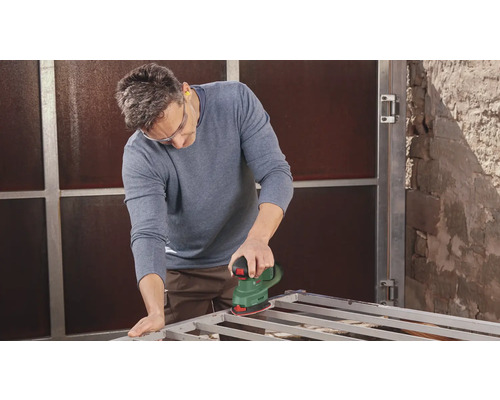 Man schuurt metalen frame met schuurmachine