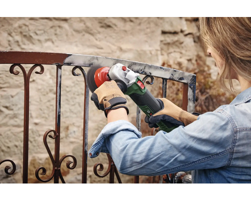 Vrouw schuurt metalen hek met een haakse slijper