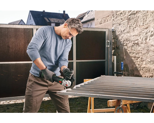 Man slijpt metalen poort met een haakse slijper in de buitenlucht.