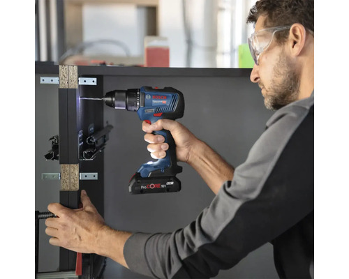 Een man boort met een Bosch accuboormachine een gat in een werkstuk.