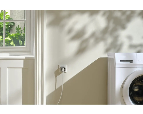 Slim stopcontact met wasmachine op de achtergrond.
