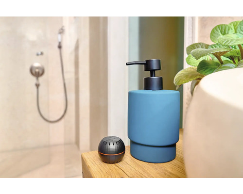 Badkamerscène met zeepdispenser en aromatherapie diffuser op een houten tafel