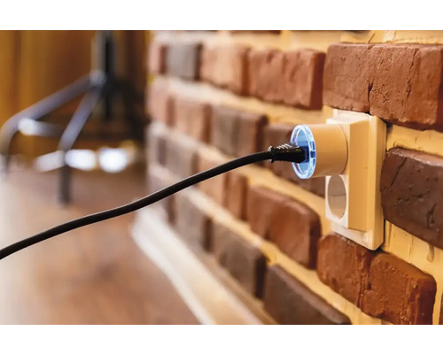 Stopcontactadapter met stekker in een bakstenen muur