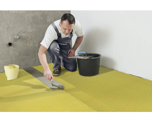 Vakman legt ontkoppelingsmat in de badkamer.