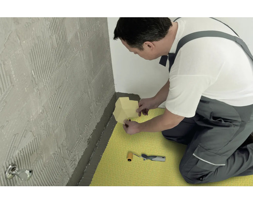 Ambachtsman brengt afdichtingstape aan in een badkamer