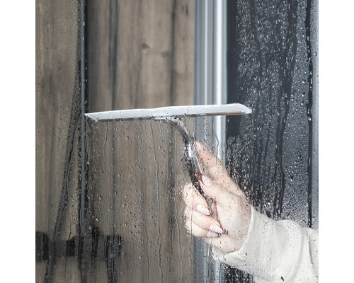 Een persoon gebruikt een douchewisser om een douchewand schoon te maken.