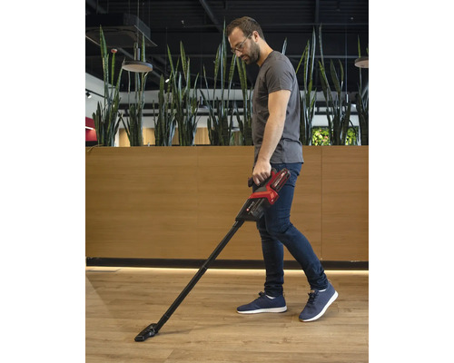 Man stofzuigt de vloer met een accustofzuiger