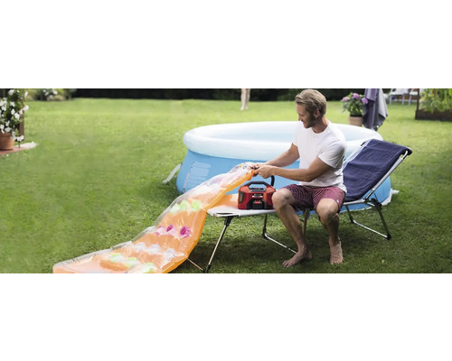 Man pompt luchtbed op met een luchtpomp in de tuin, met een zwembad op de achtergrond