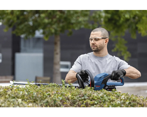 Man snoeit heg met een heggenschaar van Bosch