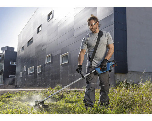 Man snijdt gras met een accugrastrimmer in de tuin