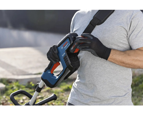 Een persoon verwisselt de accu van een Bosch accugrastrimmer met draagriem