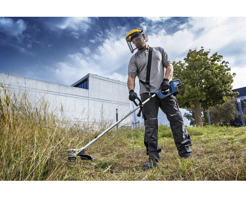 Een persoon gebruikt een grastrimmer met veiligheidsvizier in de tuin.