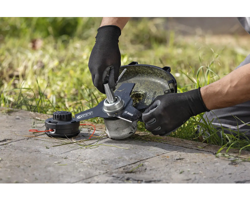 Een man vervangt het mes op een grastrimmer.