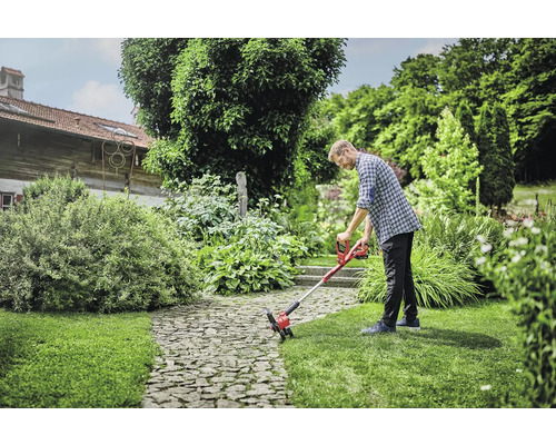 Man gebruikt een accukantensnijder in de tuin.