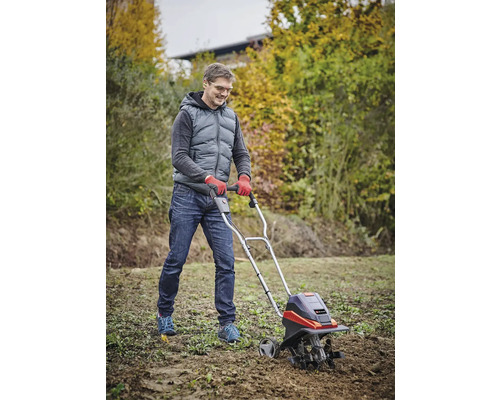 Man werkt met een tuinfrees voor grondbewerking in de tuin.