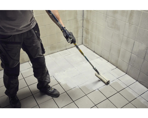 Iemand schildert tegels met een verfroller.