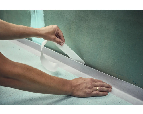 Applicatie van afdichtband in de badkamer voor het afdichten van wand en vloer.