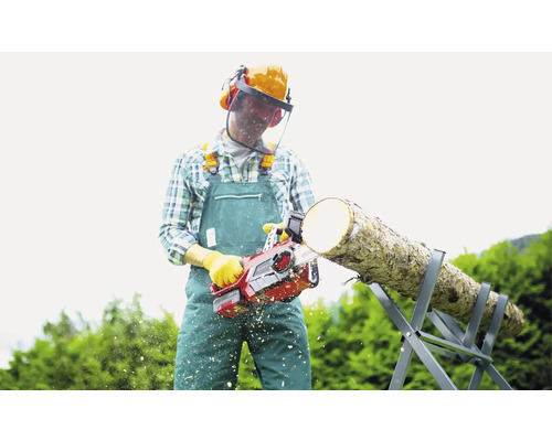 Man met veiligheidshelm zaagt hout met een kettingzaag op een zaagbok.