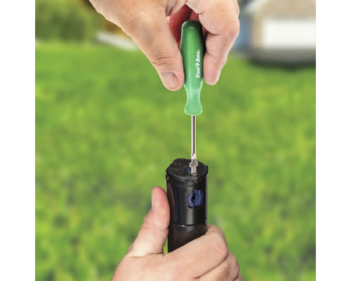 Iemand past een gazonsproeier aan met een schroevendraaier van Rain Bird.