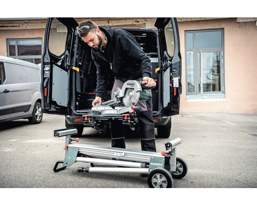 Man met Metabo verstekzaag op een zaagtafel voor een bestelwagen
