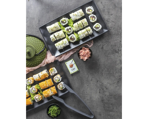 Twee serveerplanken met sushi, gember, zeewier, theepot en sushitang op een tafel