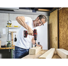 Man boort met een accuboormachine een gat in een stuk hout.