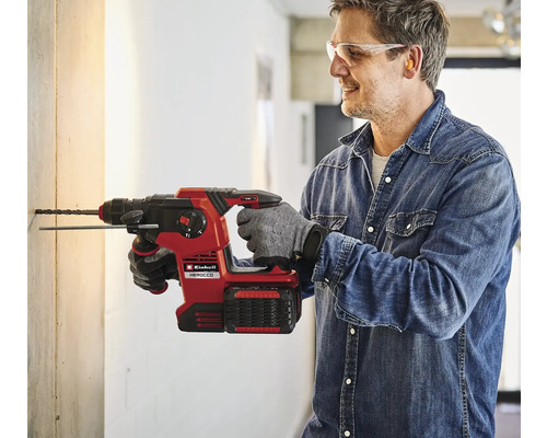 Een man boort met een Einhell Herocco accu-boorhamer een gat in een muur.